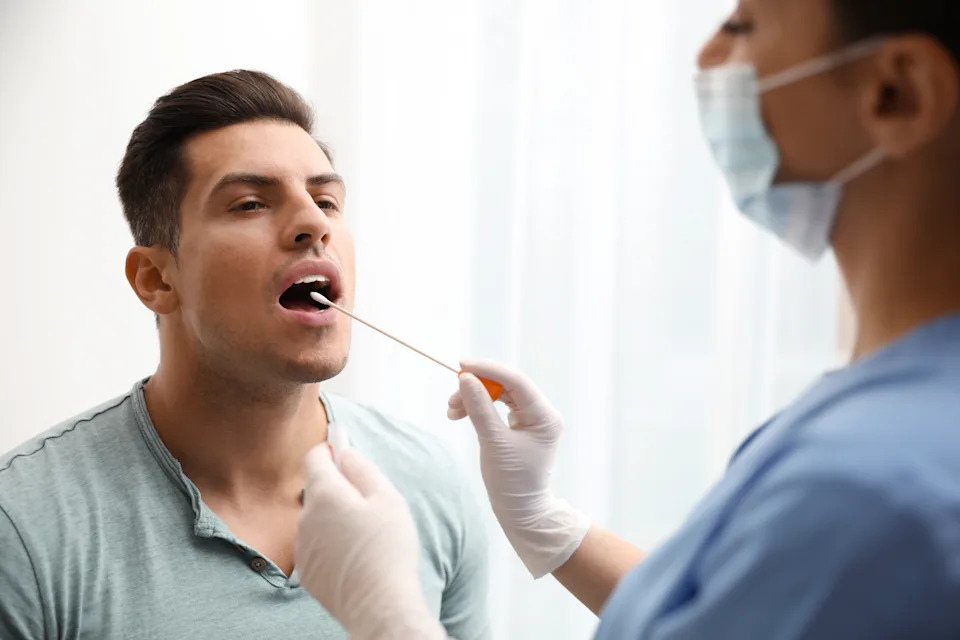A gloved hand collecting a DNA sample with a cheek swab.