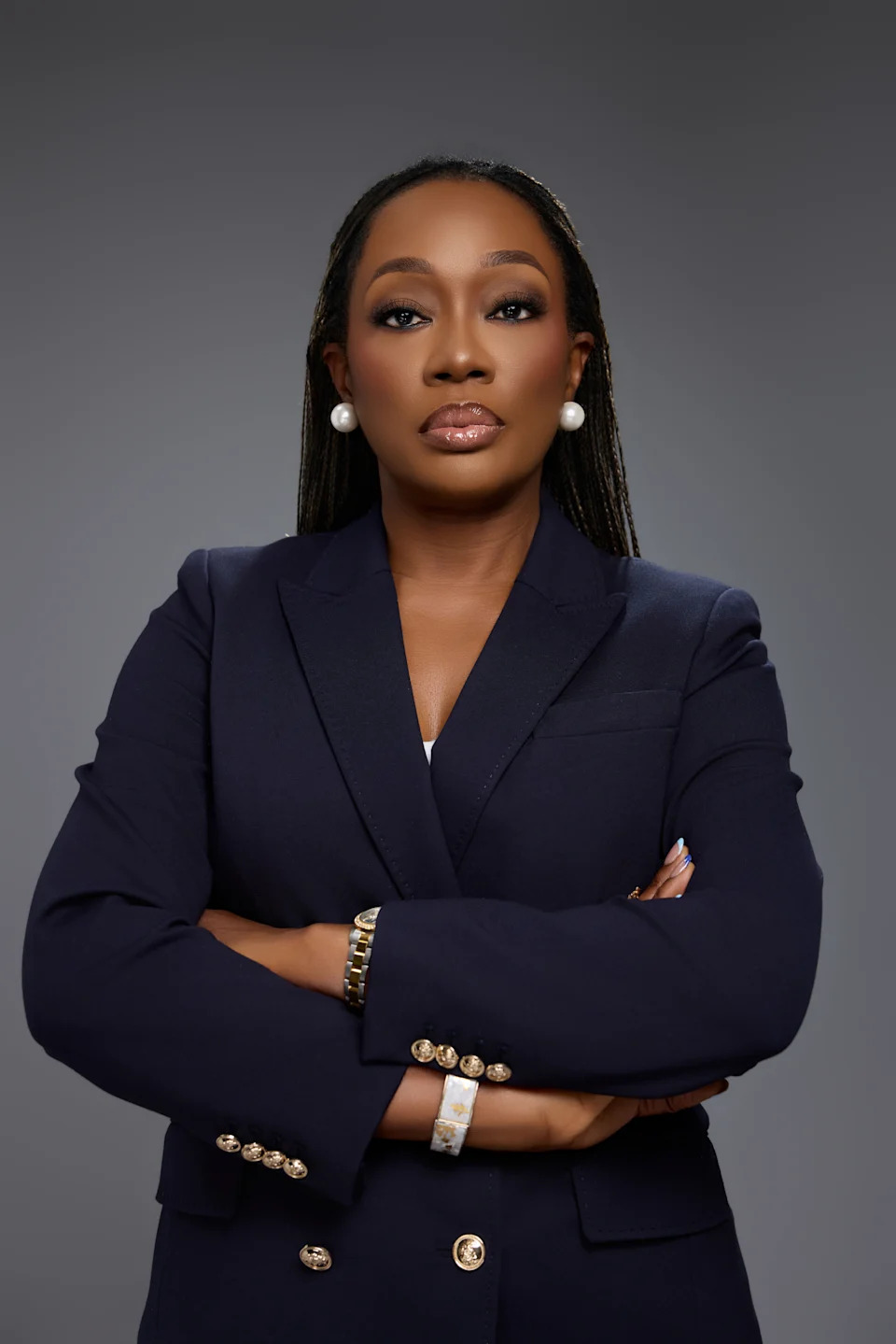 Dr. Oluwatosin Ajao, a triple board-certified obesity medicine physician, in a navy blazer against a gray studio backdrop