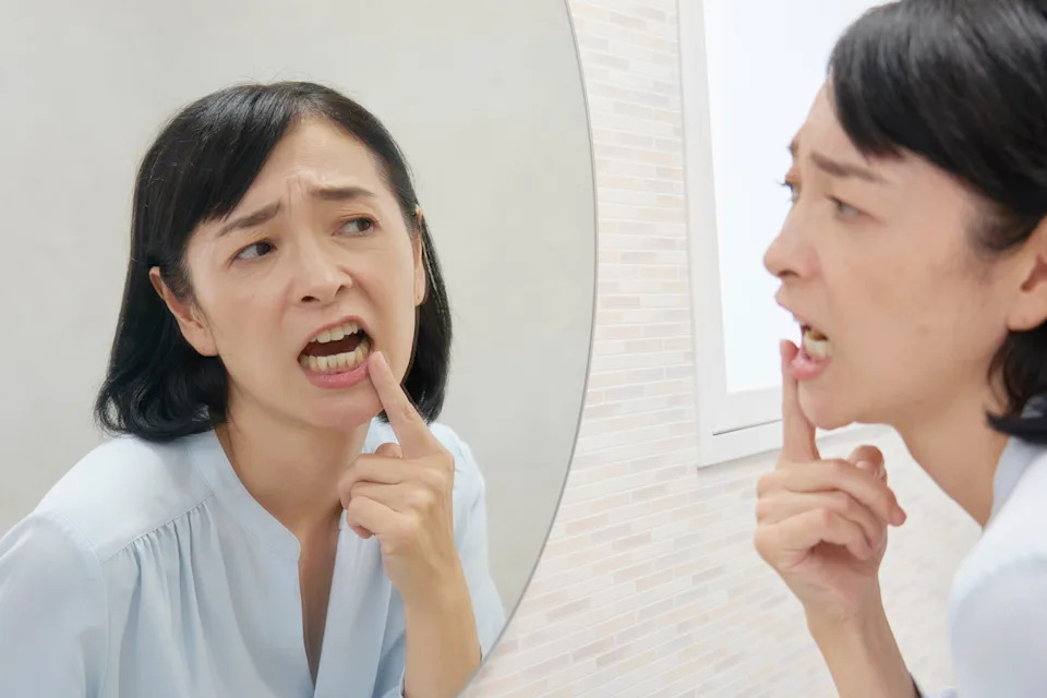 Woman leaning toward a bathroom mirror to closely examine her gums and teeth