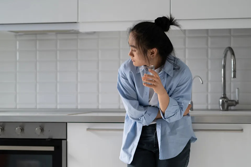 Woman drinking a glass of water at home while managing mild GLP-1 side effects