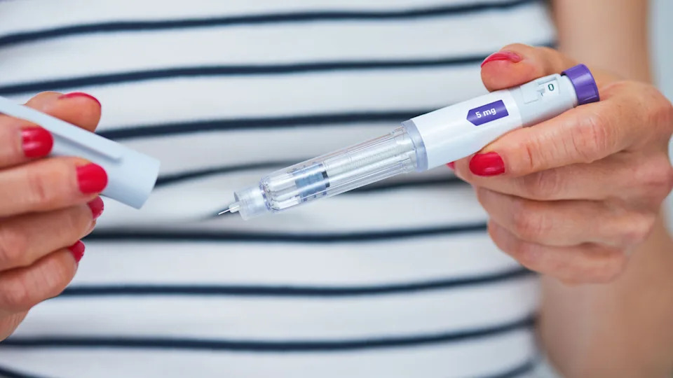 Close up of woman's hands holding a GLP-1 injector