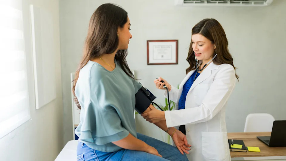 Doctor checking a patient's blood pressure during a routine exam, illustrating the link between gum health and overall health