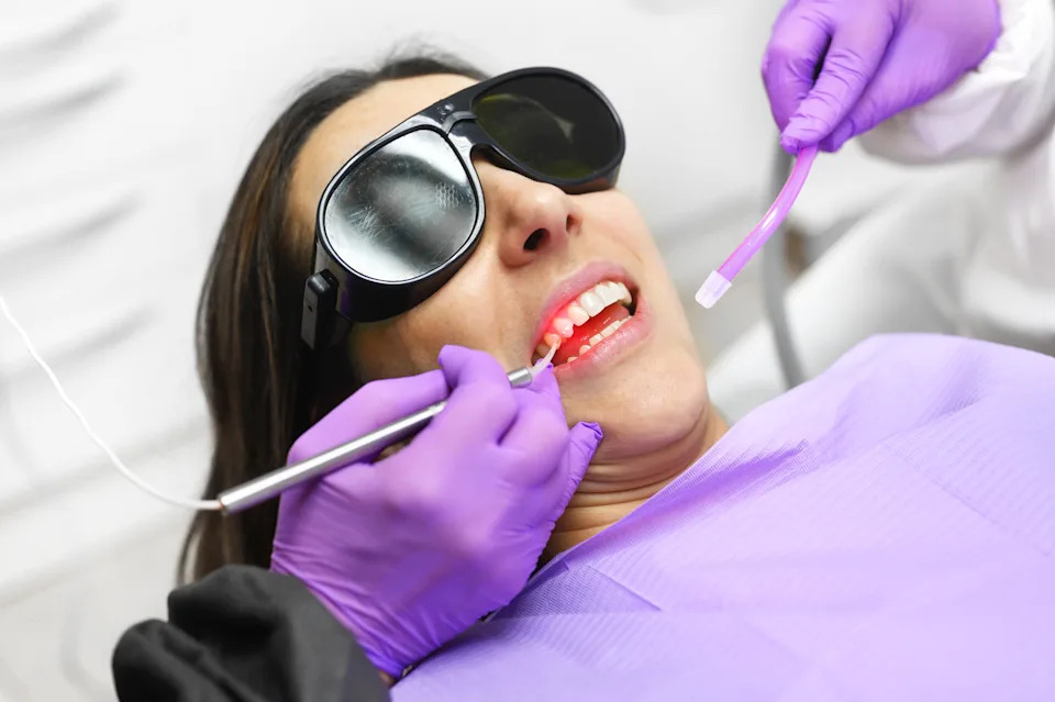 Periodontist using laser-assisted technology during a minimally invasive gum treatment on a calm patient