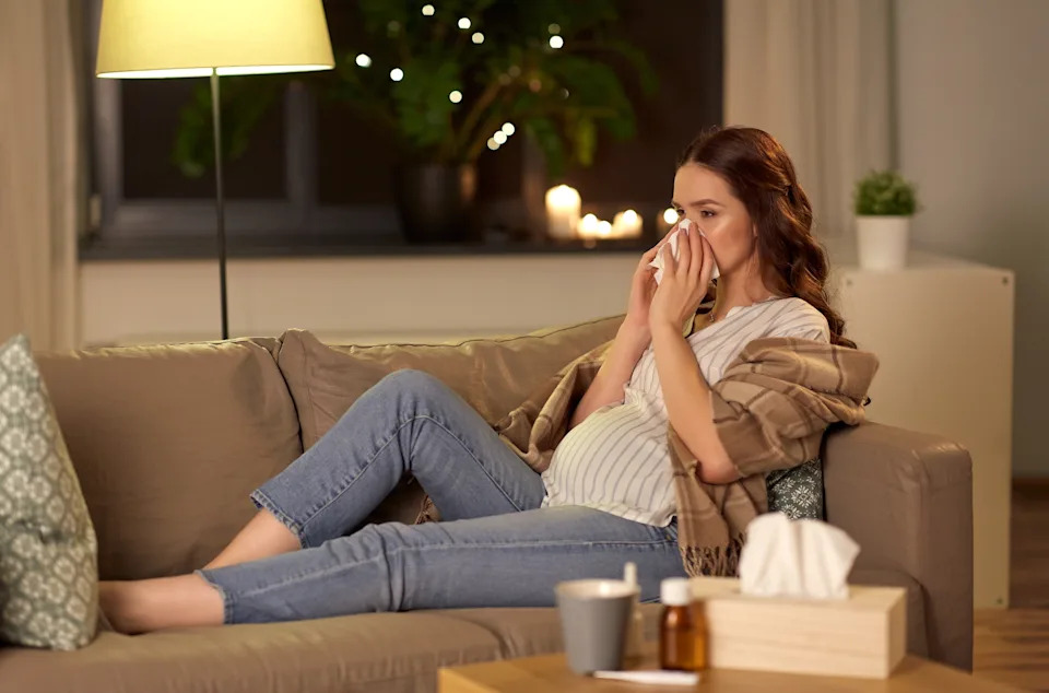 Pregnant woman blowing her nose.