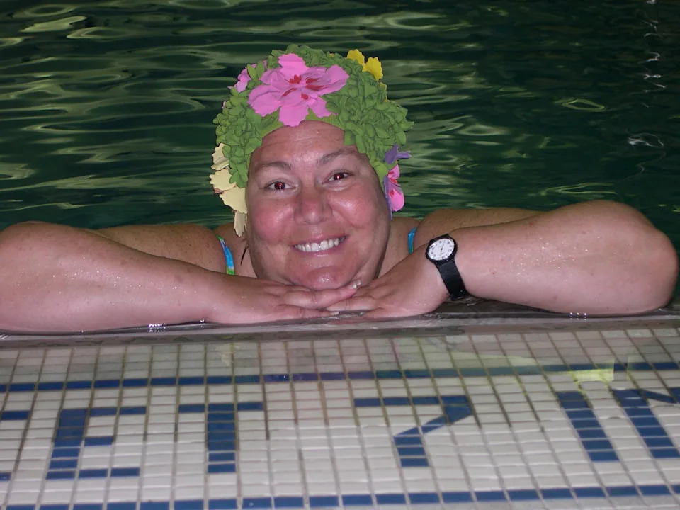 R Honig poses in the pool, her happy place, in a fun floral swim cap.