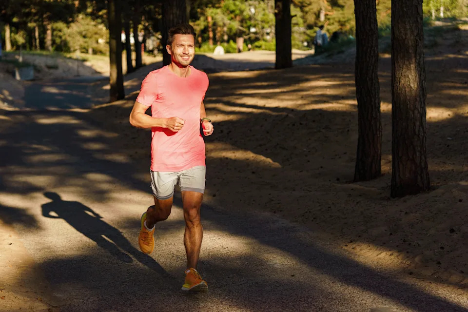Man running on a forest trail at golden hour experiencing the runner's high