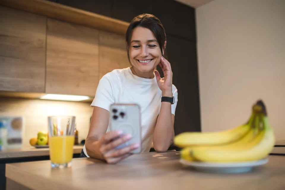 Woman at home smiling as she makes a phone call to schedule a dental appointment
