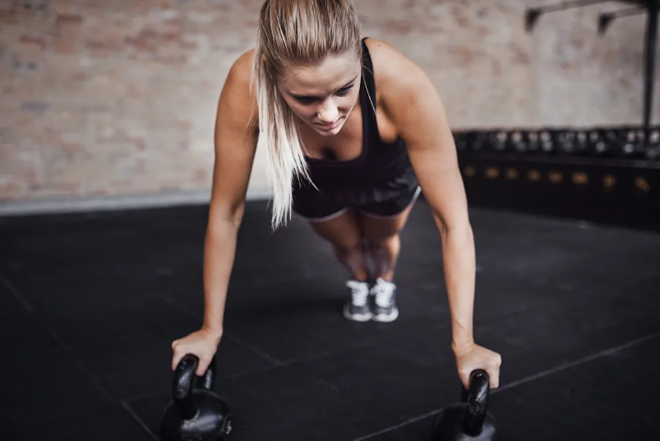 Person performing a kettlebell strength exercise during a solo workout, illustrating consistency in fitness routines.