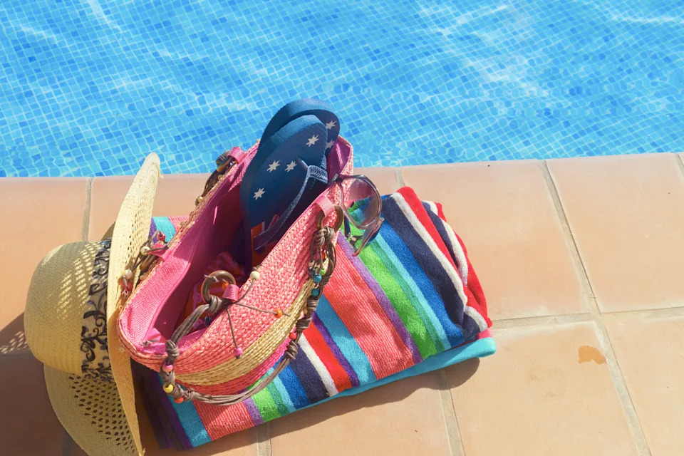 Swim bag with cap, goggles, and towel packed poolside for a morning water aerobics routine