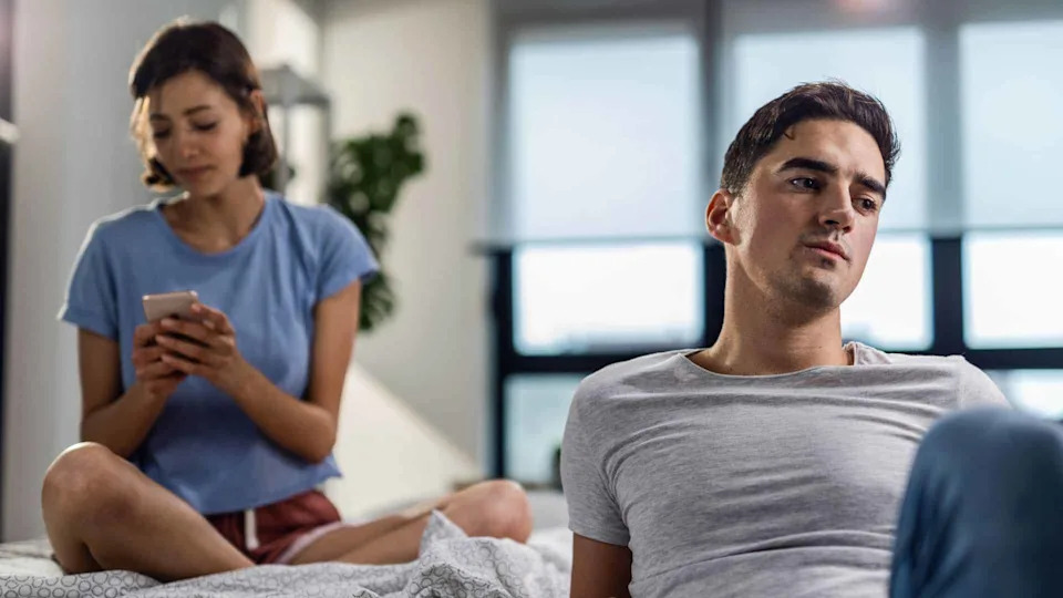 A woman using her phone and ignoring a man