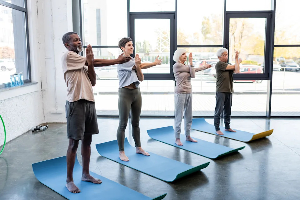 Diverse group of adults practicing yoga in a bright studio for mental health benefits