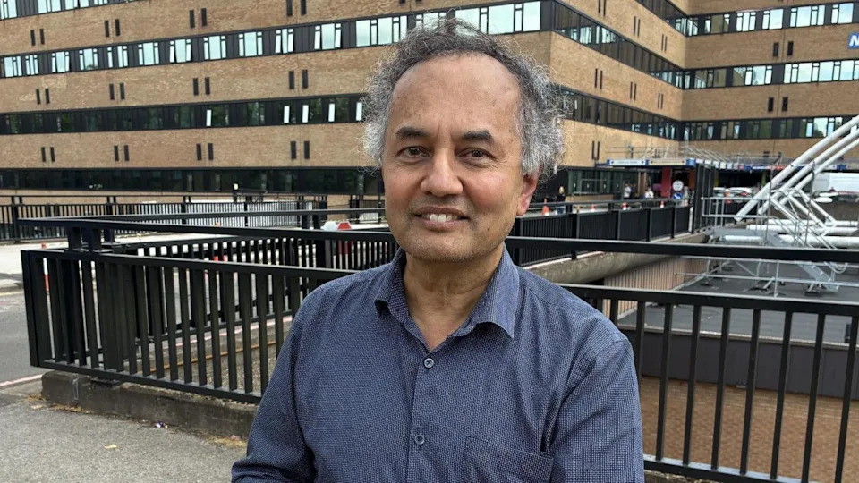 Professor Guru Aithal stood outside Nottingham's Queen's Medical Centre wearing a blue shirt