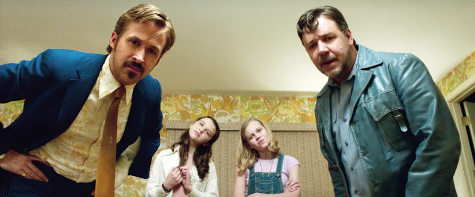 Two men in suits and two girls standing indoors, looking down intriguingly, as if investigating something
