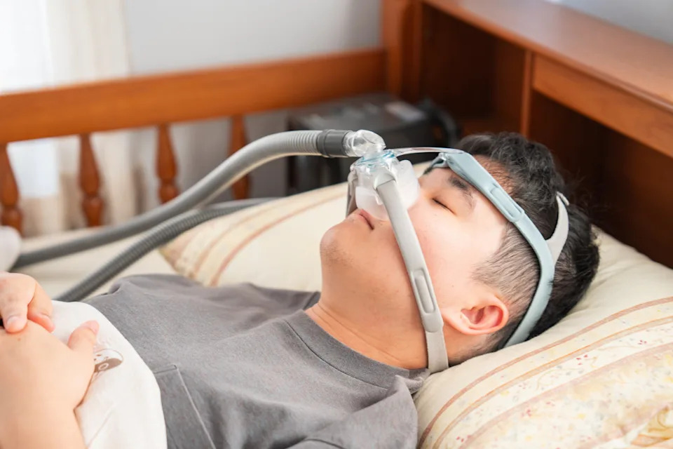 Person sleeping with a CPAP mask in bed, illustrating sleep apnea treatment