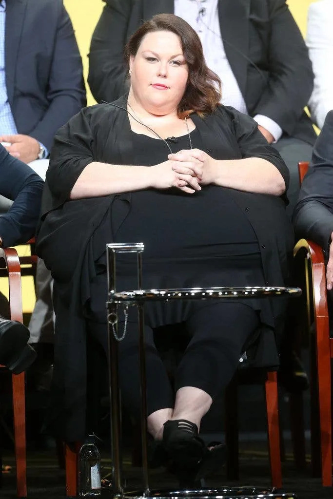 Chrissy looking sombre in black sitting in a chair