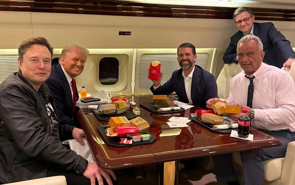 Health nut Robert F. Kennedy Jr. (right) reluctantly smiles with a McDonald's meal shortly after Donald Trump's election win. / Donald Trump Campaign