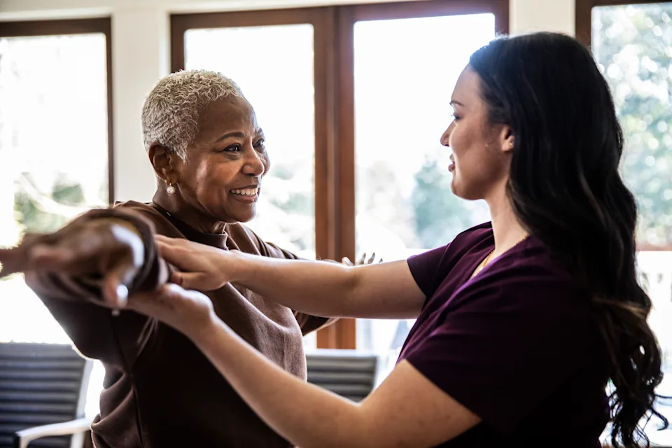 In-home nurse helping Nurse helping senior woman with physical therapy in her home man walk down hallway