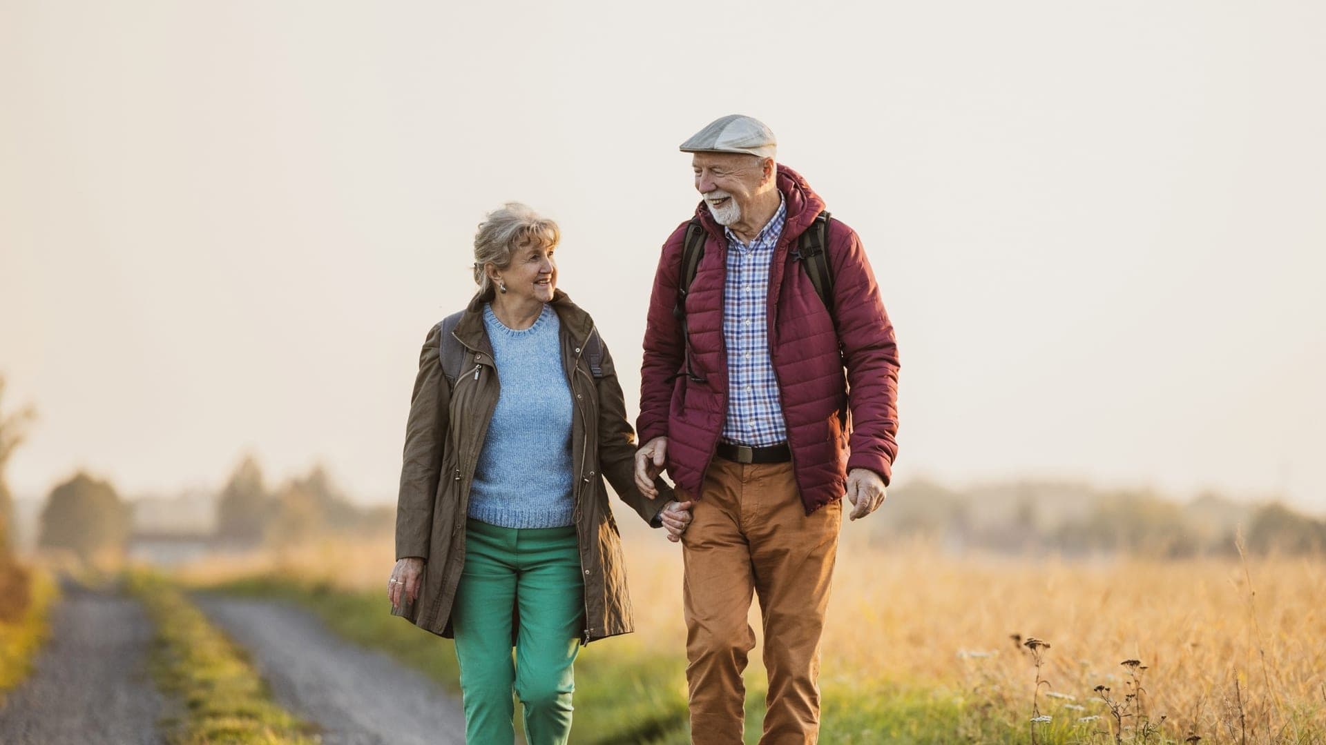 An older couple enjoys a walk together along a country path.