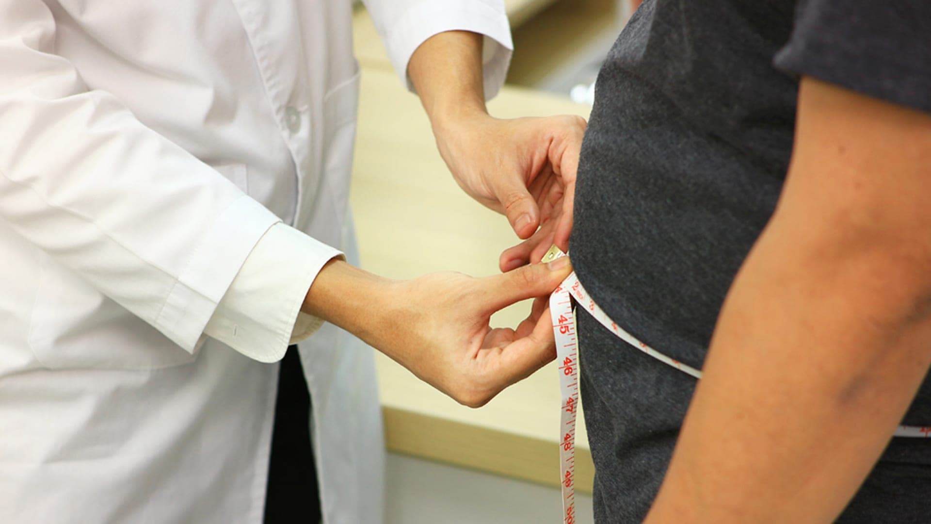 A healthcare professional measures a patient’s waist during a physical assessment. Credit: Shutterstock