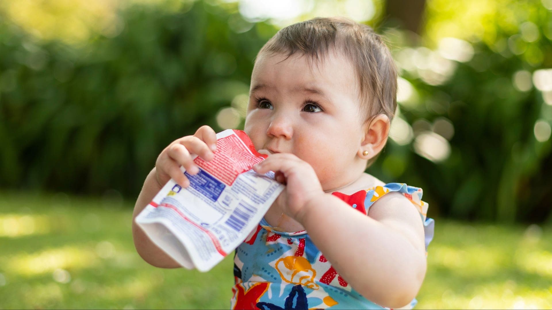 A baby enjoys food from a pouch while spending time outdoors. Credit: Shutterstock