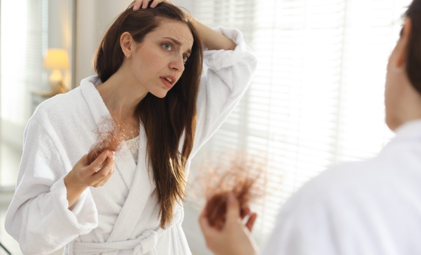 Woman examining a clump of shed hair, illustrating the GLP-1 hair loss side effect.