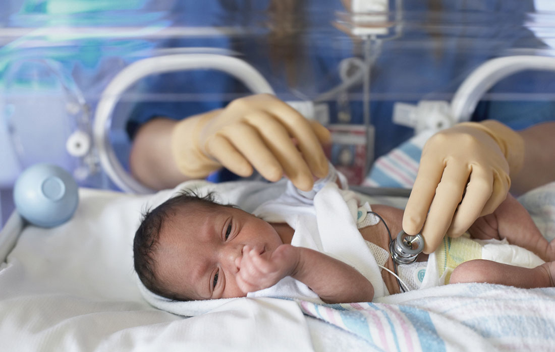 Female doctor examining newborn baby in incubator