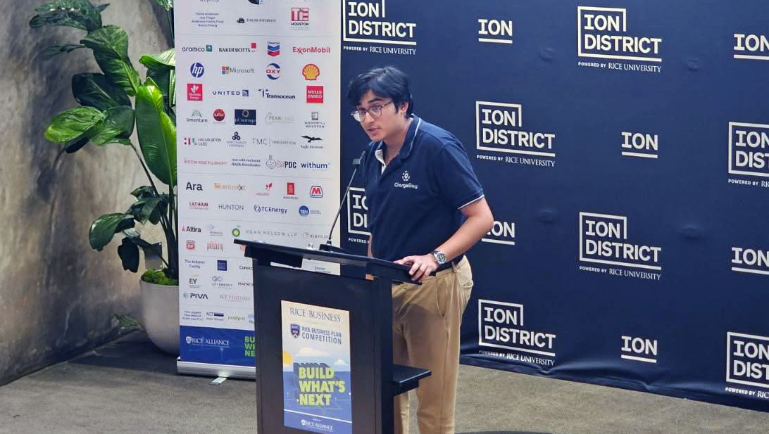 Ansh Bhatt speaks at a podium during the Rice Business Plan Competition, with Ion District branding and sponsor logos displayed behind him.