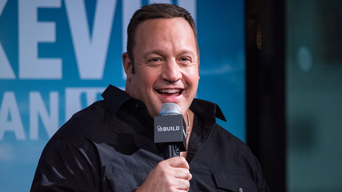 Kevin James wearing a black polo speaking into the microphone at the AOL Build.