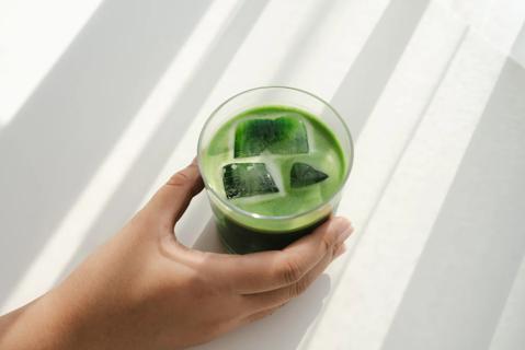 Hand reaching for a glass of iced matcha