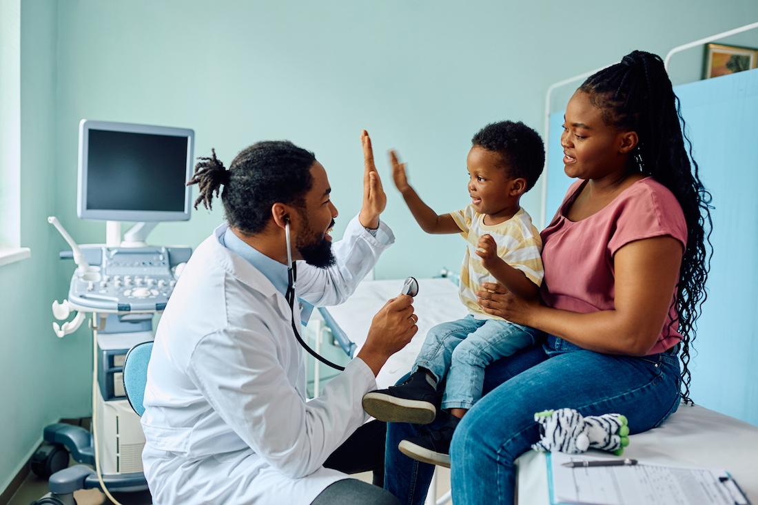 Happy boy giving high five to his pediatrician after medical examination at doctor's office.