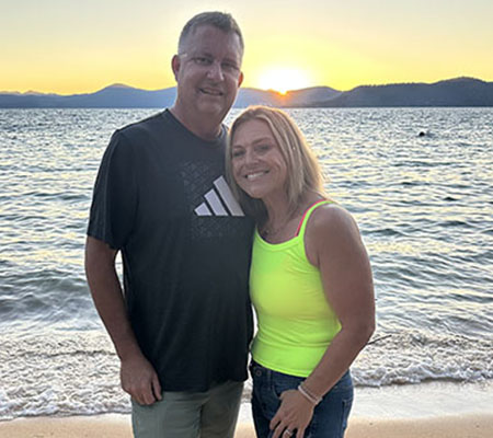 A man and woman with arms around each other at sunset on a beach.