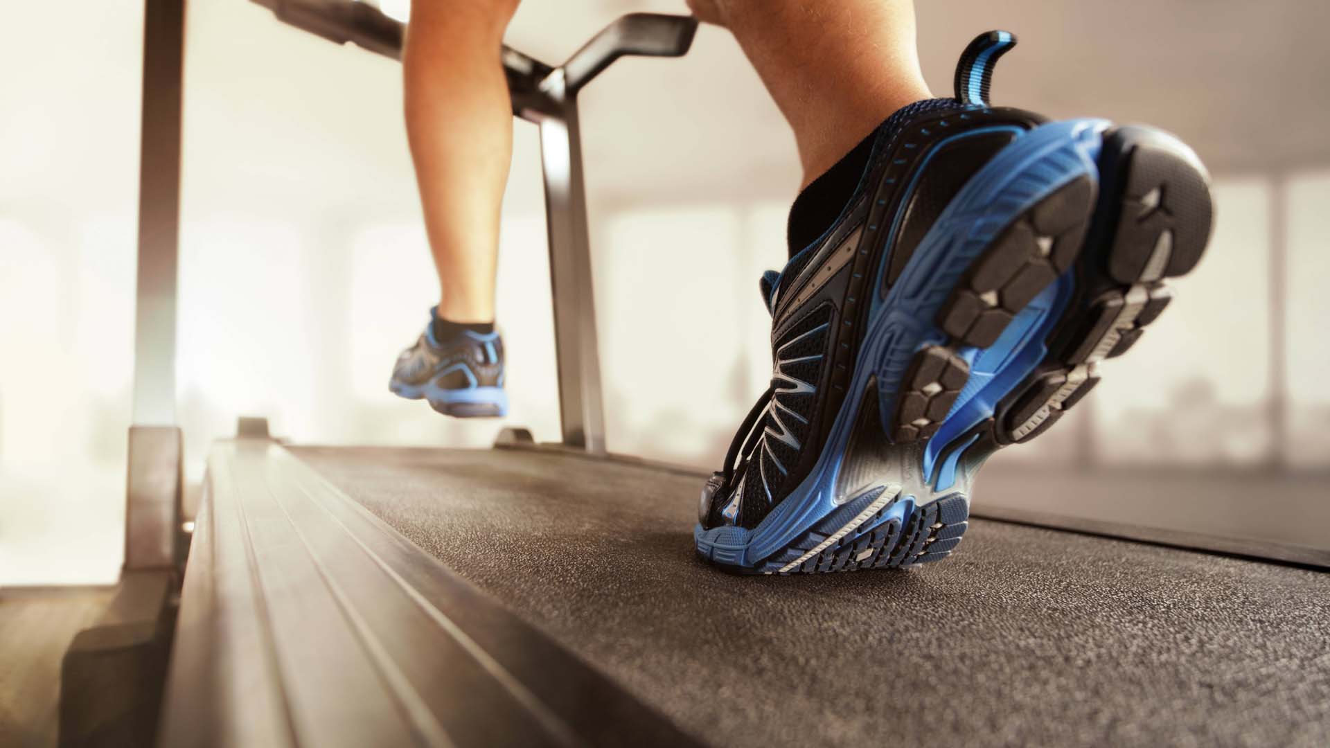 Person running on treadmill with just below the knee showing and sunlight in the background