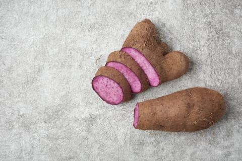 A fresh, sliced ube, with purple insides, and a fresh, whole ube