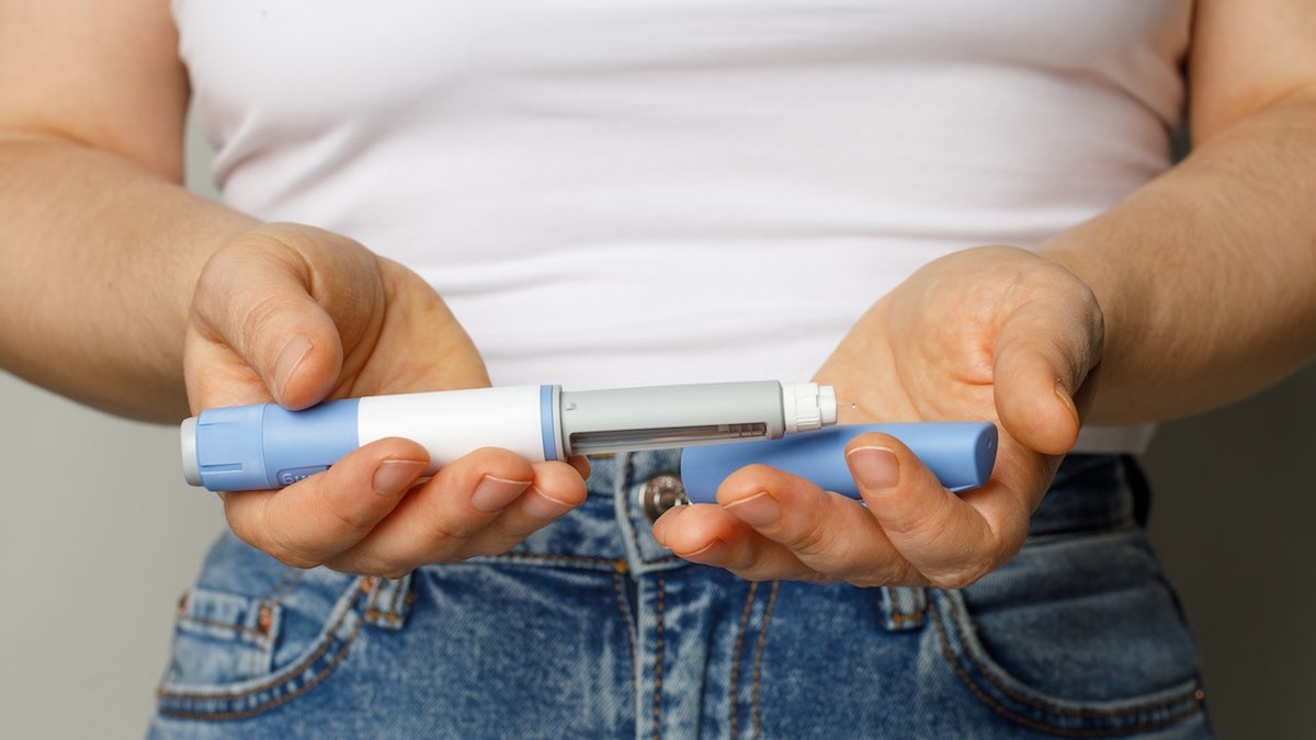 Woman holding weight-loss injection pen