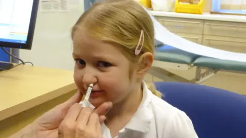 UKHSA A girl getting her nasal flu vaccine from her GP