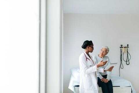Healthcare provider talking to patient seated on exam table