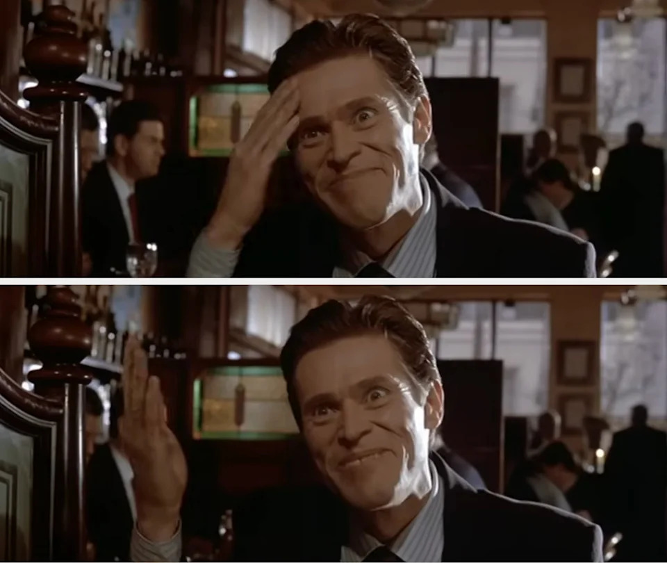Person in a suit at a restaurant, with a playful expression, touching their forehead