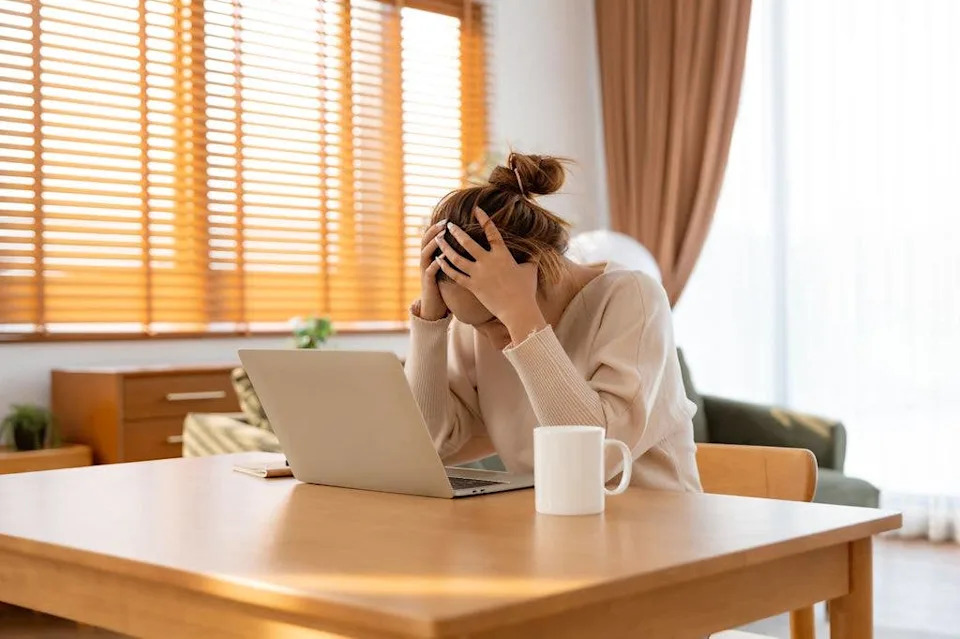 woman suffering stress at table with laptop computer