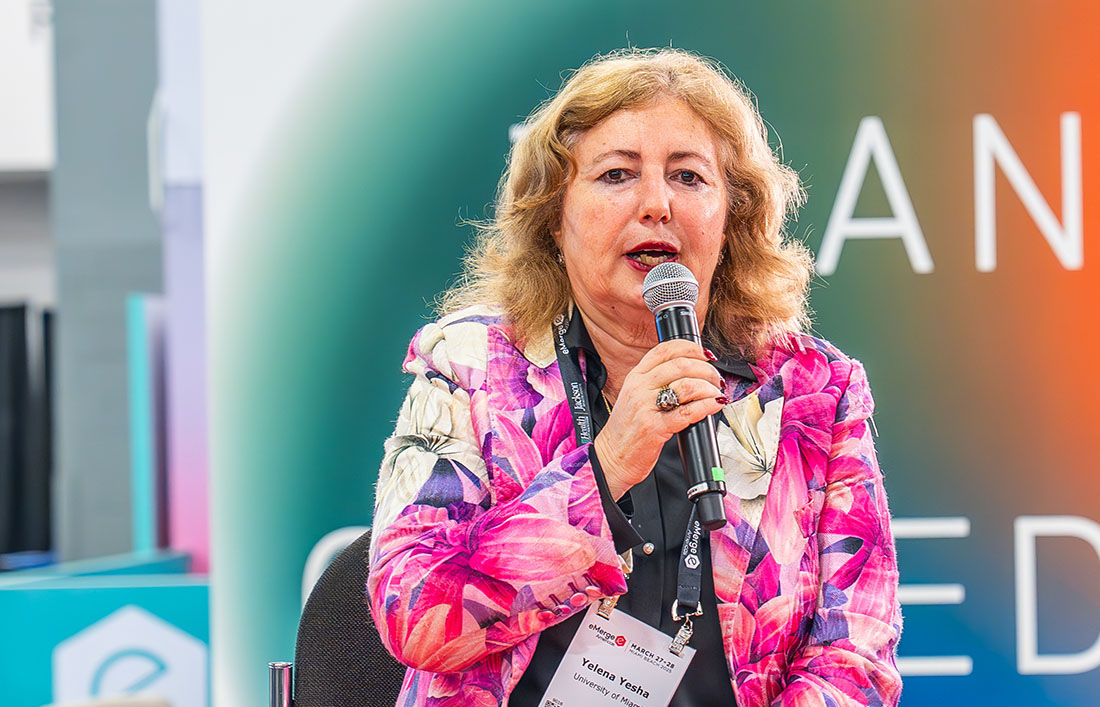 Dr. Yelena Yesha speaks at Miami Valves. She's seated onstage and speaking into a microphone.